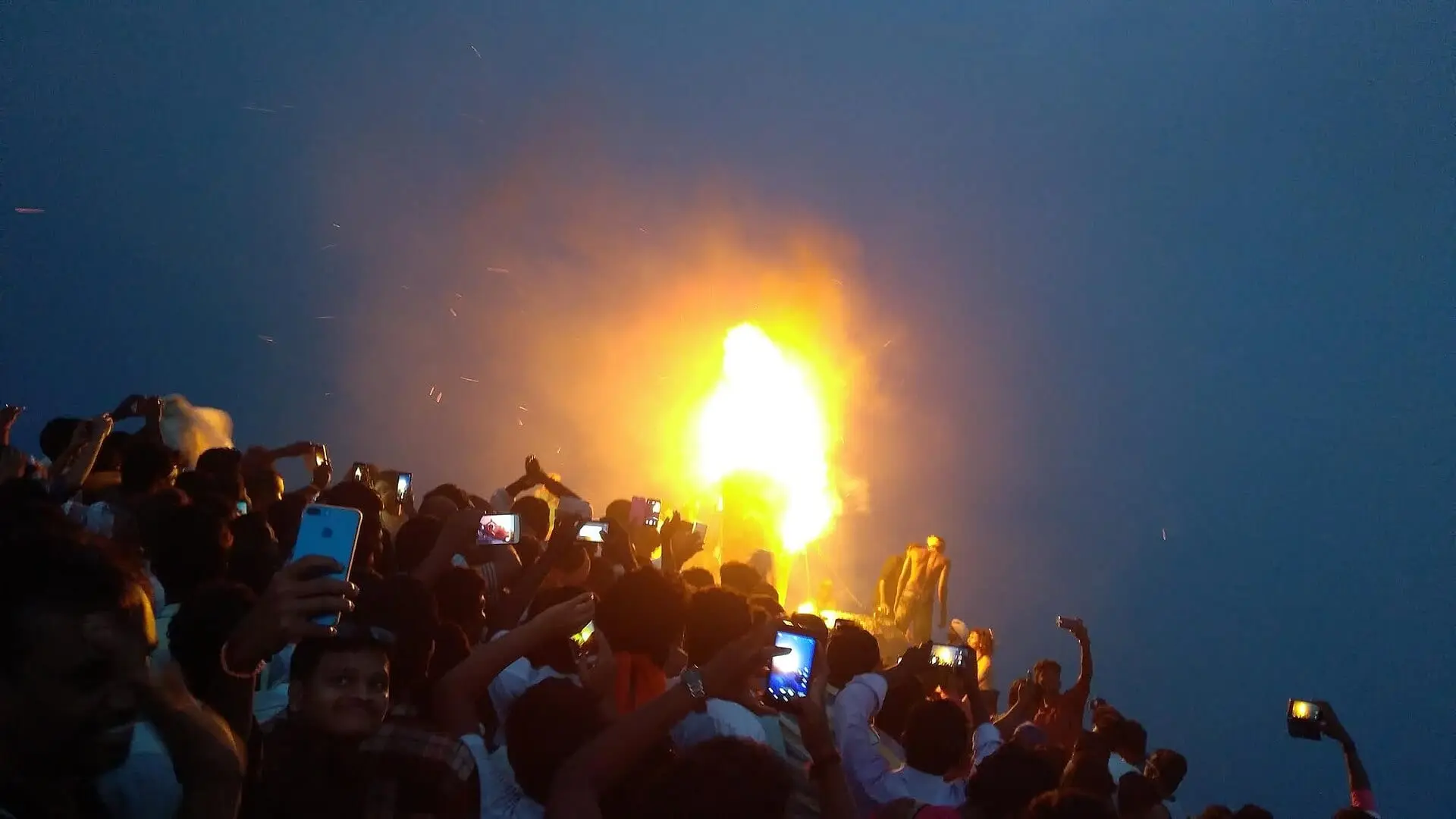 Devotees on the summit watch the Maha Deepam flame blaze at dusk during Karthigai Deepam