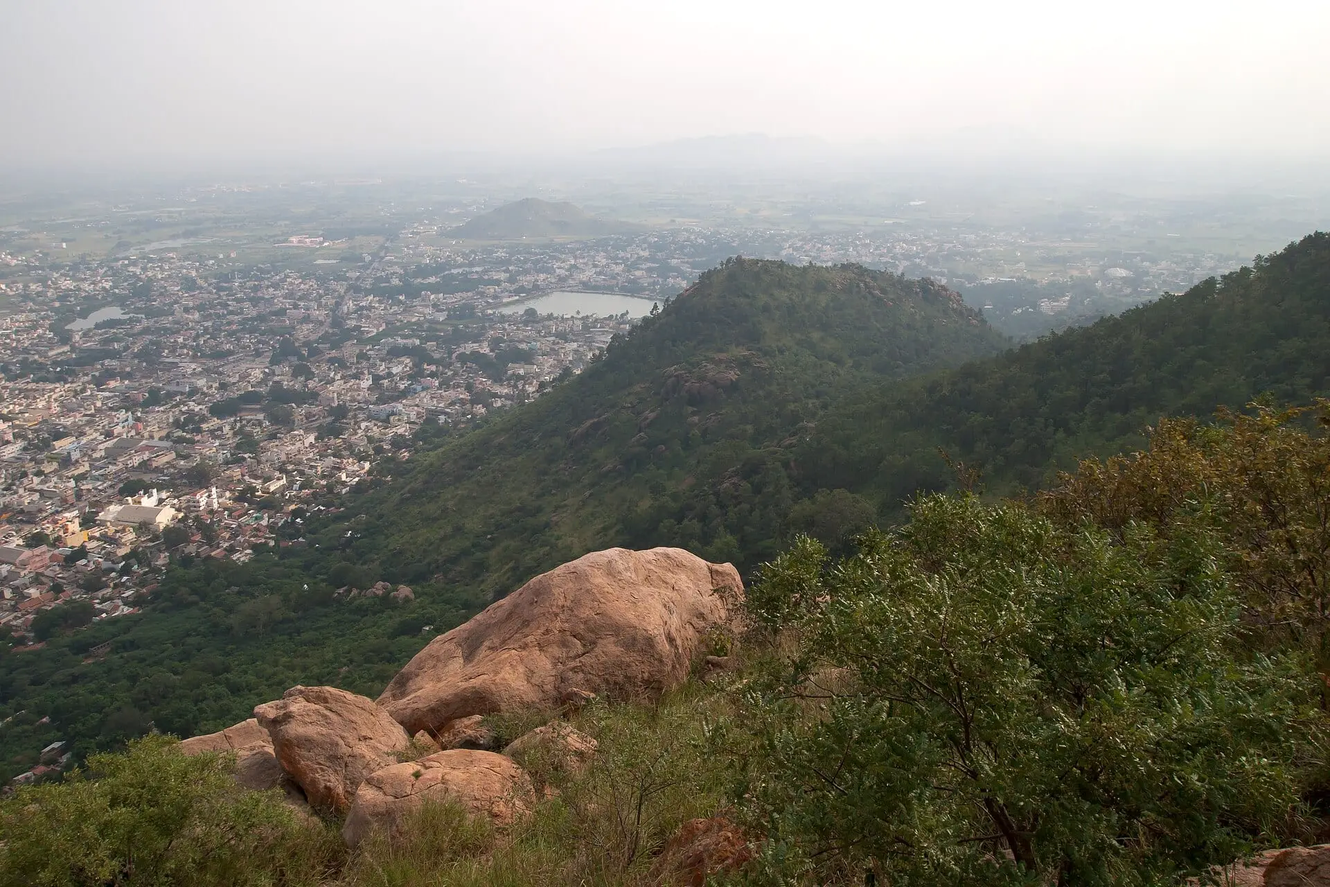 Granite boulders and green slopes of Arunachala hill looking down on Tiruvannamalai and its temple tank