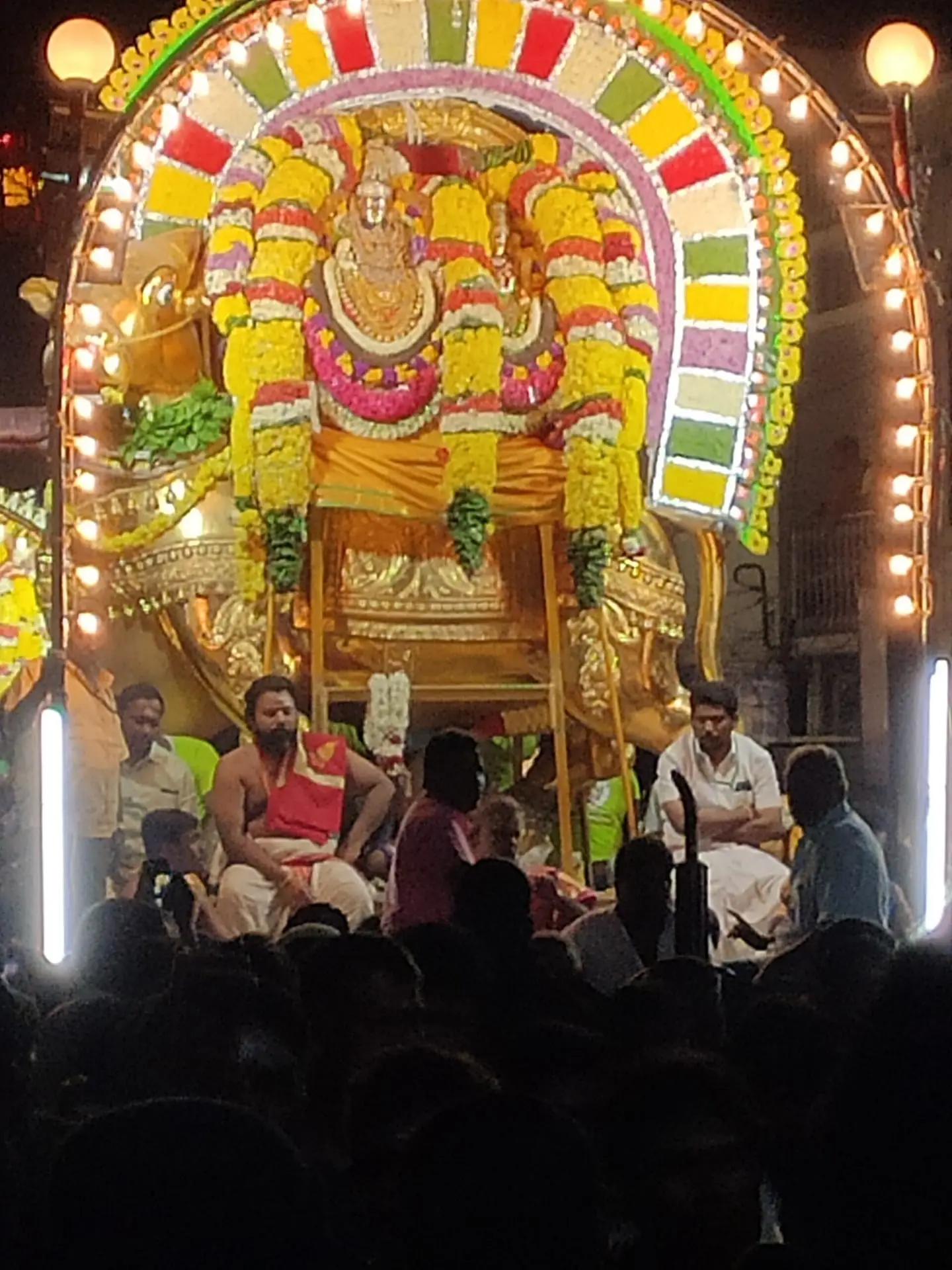 A festival deity decorated with flower garlands on a golden vahana during a night procession in Tiruvannamalai
